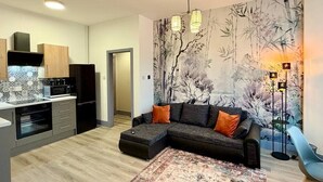 A modern kitchen with a microwave, oven, and cabinets, a dark sectional sofa with orange cushions, and a patterned rug. - 1 Spacious 1-Bed Flat Sleeps 3 Secure Parking WiFi (Cleethorpes)