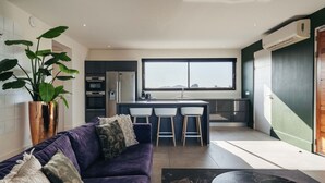 A modern kitchen with a central island, bar stools, and a large window. - Jan Sofat LUX 2BR Penthouse Pool + Mountain View (Willemstad)