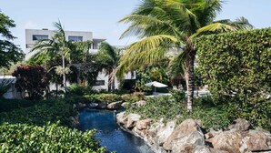 A pool surrounded by rocks and palm trees, with a building in the background. - Jan Sofat LUX 2BR Penthouse Pool + Mountain View (Willemstad)
