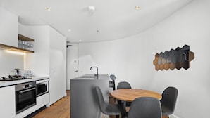 Une cuisine moderne avec un îlot central, des chaises grises et une table à manger en bois.