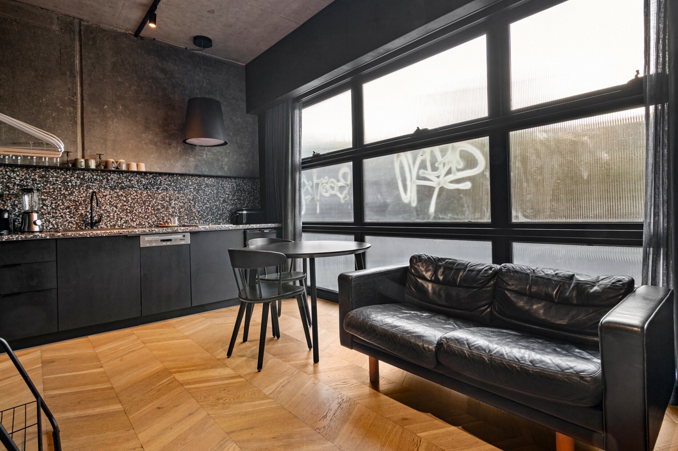 Una cocina moderna con comedor, ventanas amplias y un sofá de cuero.