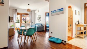 A spacious living area with a dining table, chairs, a sofa, and a pet bed. - Domus Quinqueremi (roma)