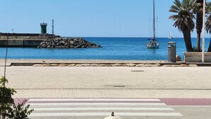 A coastal promenade with a lighthouse, a sailboat, and palm trees. - Domus Quinqueremi (roma)
