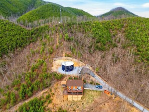 A remote cabin with a large water tank, surrounded by dense forest and hills. - Gatlinburg Cabin • Pool Table • Pool • Hot Tub • Sleeps 10 | Cobbly Nob Hideaway (Gatlinburg)