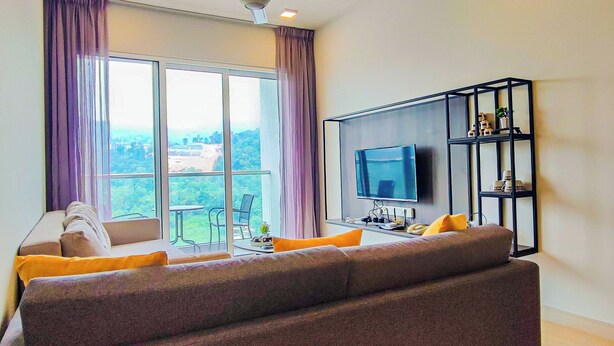 Een woonkamer met een bank, een televisie en een balkon met uitzicht.