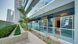 Um edifício moderno com grandes janelas, um jardim no terraço e vista para outros edifícios altos.