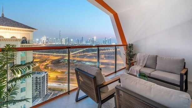 Un balcon moderne avec vue sur la ville, un canapé, un fauteuil et une plante en pot.