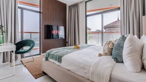 Une chambre d’hôtel moderne dotée d’un grand lit, d’un bureau, d’une télévision et offrant une vue sur la ville.