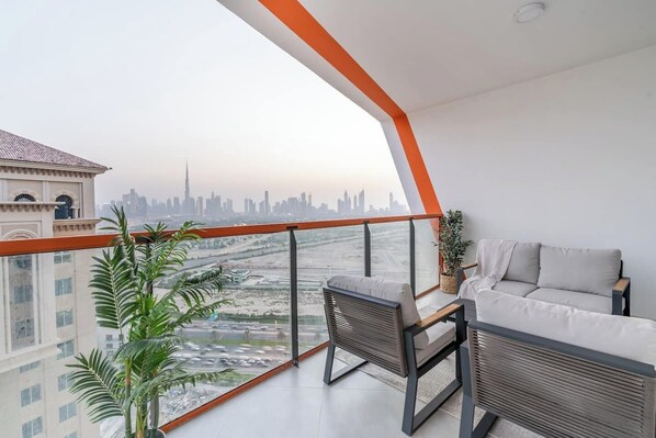 Ein Balkon mit Blick auf eine Stadtlandschaft, einer Couch und einem Tisch.