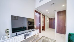 A modern living room with a large flat-screen TV, a white console table, and a green sofa. - Vera Residence - 1303 (Dubai)