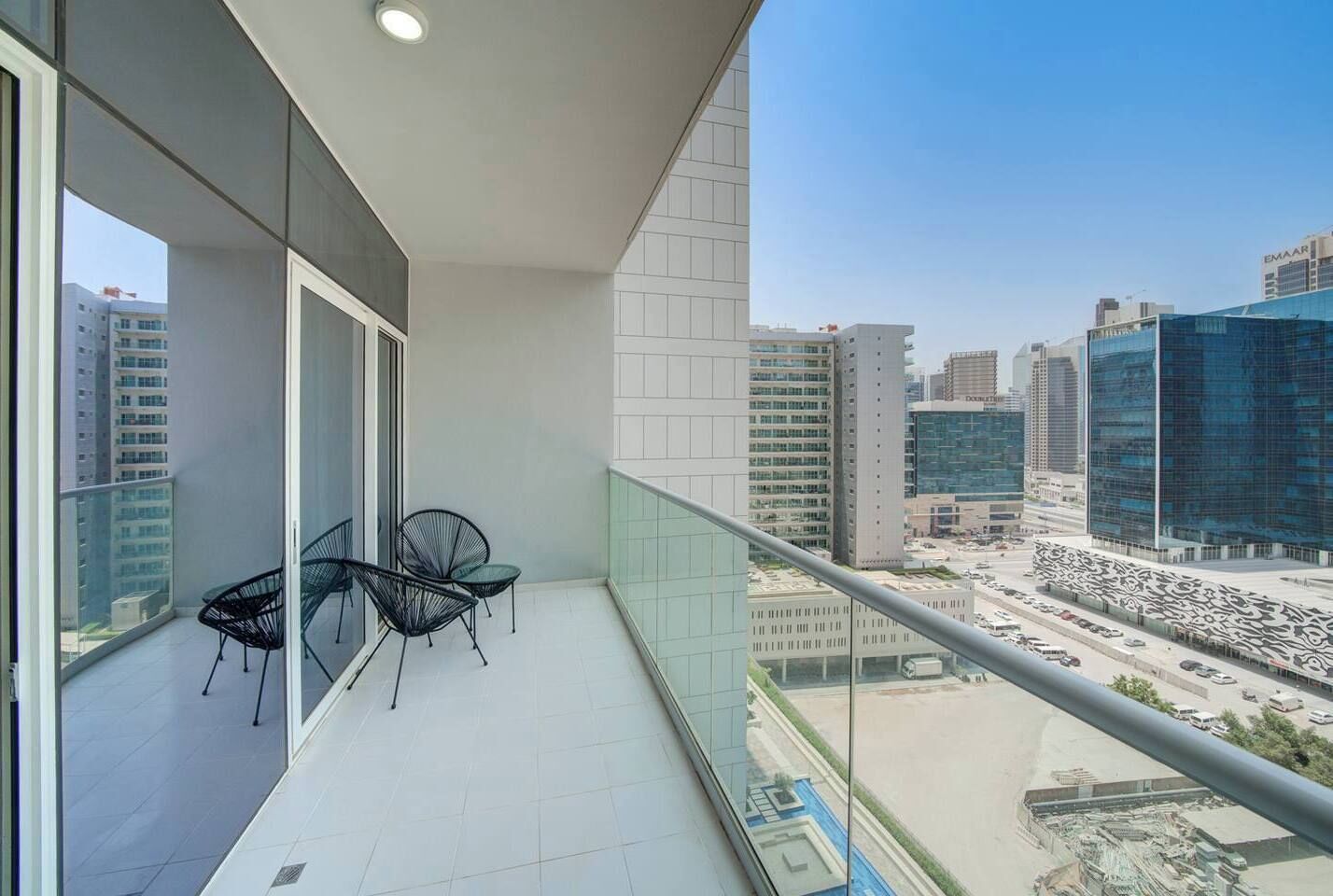 A balcony with a view of a cityscape, including modern buildings and a parking area.