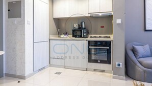 Une cuisine moderne dotée d’appareils électroménagers intégrés, un coin repas avec un canapé gris et un sol carrelé.