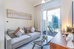 A modern living room with a sofa, a glass coffee table, and a view of a cityscape through large windows. - Vera Residence - 1120 (Dubai)