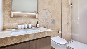 Une salle de bain moderne avec un lavabo en marbre, des toilettes et une douche à parois de verre.