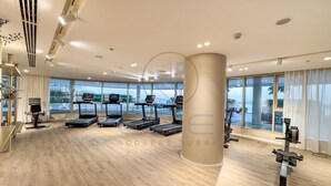 Une salle de sport moderne équipée de tapis de course, de vélos d’appartement et d’une grande fenêtre donnant sur l’extérieur.