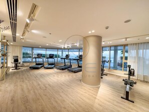 Ein modernes Fitnessstudio mit Laufbändern, Ergometer und einem großen Fenster mit Blick ins Freie.