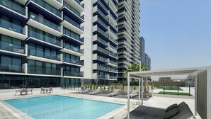 A modern hotel with a rooftop pool, outdoor seating, and a view of the cityscape. - Binghatti Corner - 1508 (Dubai)