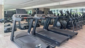 A gym with multiple treadmills, exercise bikes, and other fitness equipment. - Binghatti Corner - 1508 (Dubai)