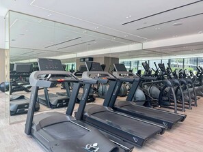 A gym with multiple treadmills, exercise bikes, and other fitness equipment. - Binghatti Corner - 1508 (Dubai)