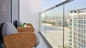 Ein Balkon mit Korbstühlen, einer Topfpflanze und Blick auf eine Stadtlandschaft.