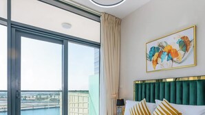 A hotel room with a large window, a green upholstered headboard, and a colorful abstract painting on the wall. - Zada Tower | 1BR, Big Balcony, Bright & Breezy (Dubai)