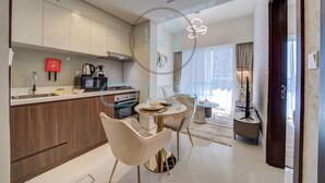 A modern kitchen with a dining area, a coffee machine, and a red fire safety sign. - Vera Residence - 814 (Dubai)
