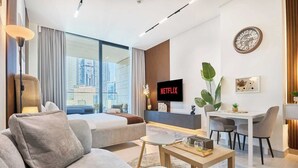 Et moderne hotelværelse med en stor seng, en sofa, et spiseområde og et fjernsyn, der viser 'NETFLIX'.