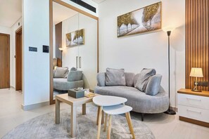 Ein modernes Wohnzimmer mit einem grauen Sofa, einem kleinen runden Tisch, einem Spiegel und einem Gemälde an der Wand.