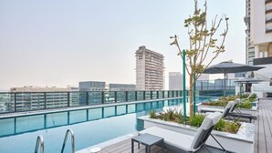 A rooftop pool area with lounge chairs, a small table, and a tree. - The Crest C Luxury Retreat | Stylish & Serene (Dubai)