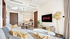 A modern living room with a sofa, coffee table, and a flat-screen TV displaying 'NETFLIX'. - The Crest C Luxury Retreat | Stylish & Serene (Dubai)