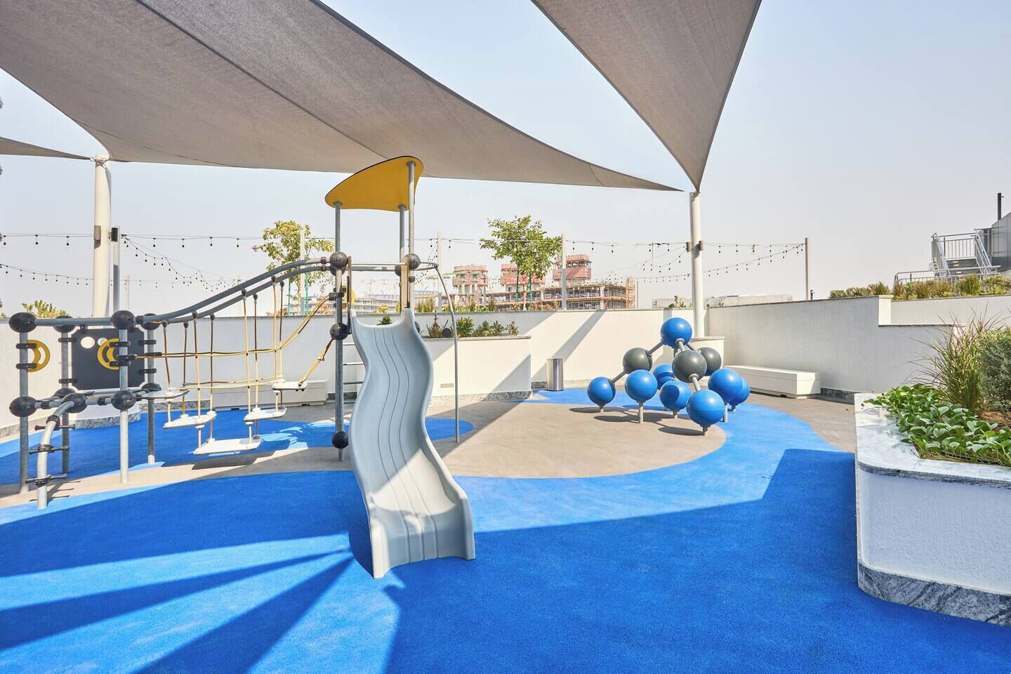 Une aire de jeux avec un toboggan, des structures d’escalade et des appareils de musculation.