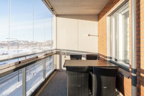 A balcony with a table and chairs, a view of a snowy landscape, and a brick wall. - Bright 2BR Apartment with Lake Views (Jyväskylä)