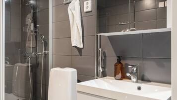 Een moderne badkamer met toilet, douche, wastafel en spiegel.