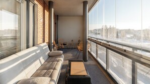 Ein Balkon mit einer Couch, Stühlen und Blick auf eine verschneite Landschaft.