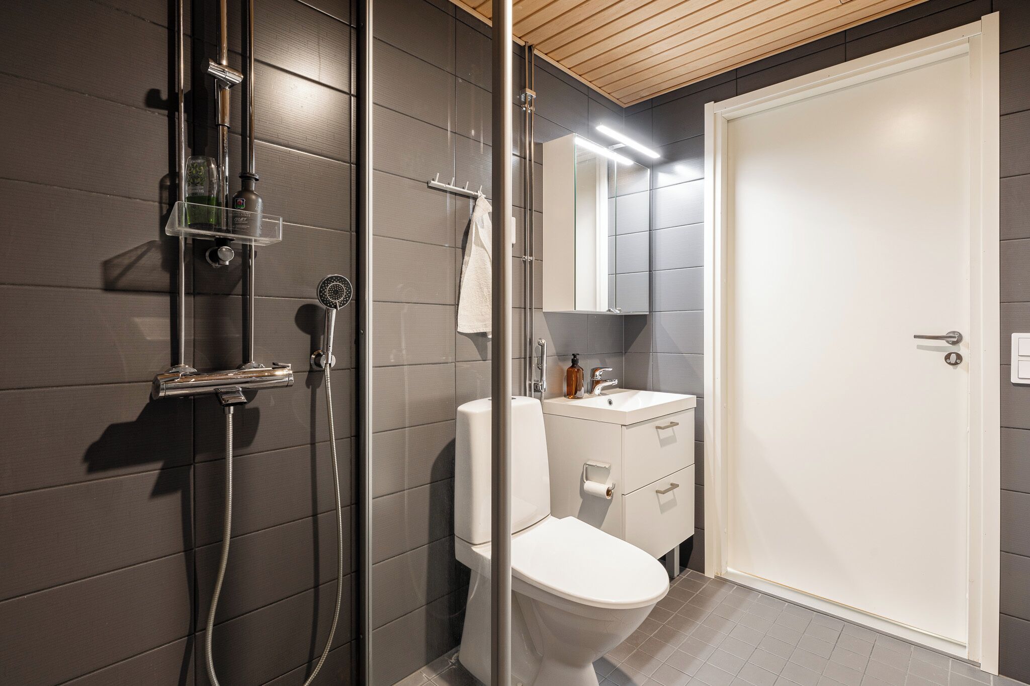 Un baño moderno con cabina de ducha de vidrio, inodoro, lavabo y espejo.