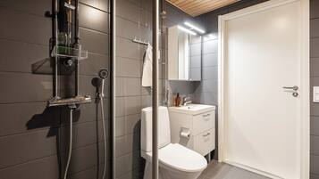 Un baño moderno con cabina de ducha de vidrio, inodoro, lavabo y espejo.