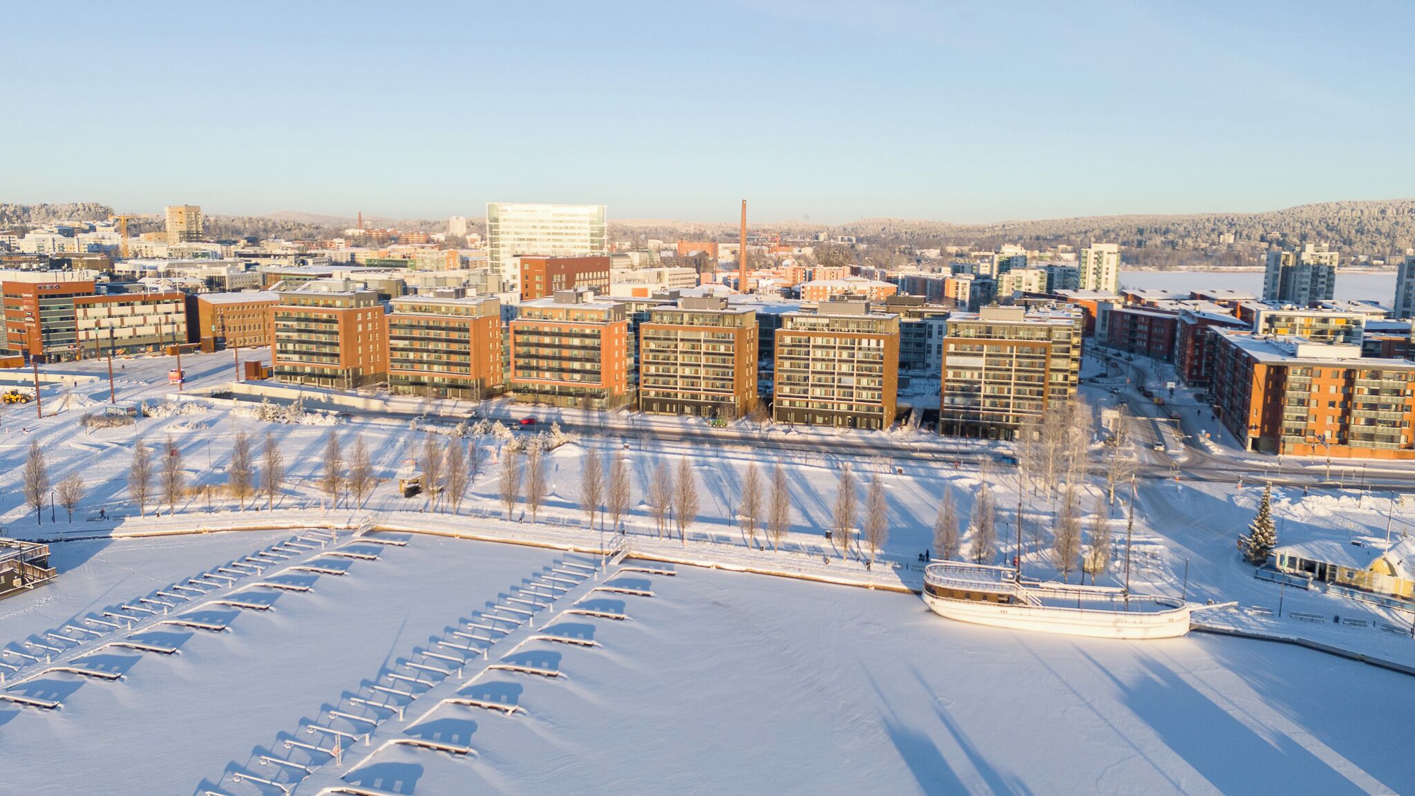 Un complesso residenziale di grattacieli con diversi condomini, un parcheggio e un paesaggio innevato.