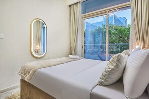 A bedroom with a bed, a mirror, and a window with curtains. - Vera residence - 403 (Dubai)