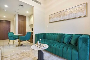 A modern living room with a teal sofa, a round coffee table, and teal chairs. - Vera residence - 403 (Dubai)