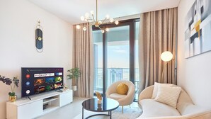 Een moderne woonkamer met een flatscreen televisie, een ronde salontafel, een bank, een fauteuil en een groot raam met gordijnen.