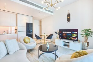 A modern living room with a flat-screen TV, two chairs, a sofa, and a dining area. - Beachfront 1BR Retreat at Address JBR (Dubai)
