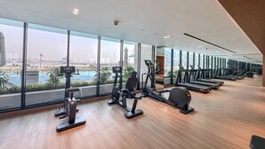 A gym with cardio machines, a pool view, and large windows. - Modern Chic Studio Featuring Skyline Views (Dubai)