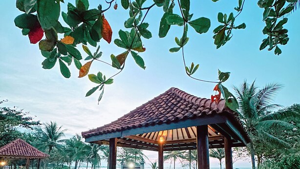 Zona junto a la piscina con un pérgola, asientos y vista al agua.
