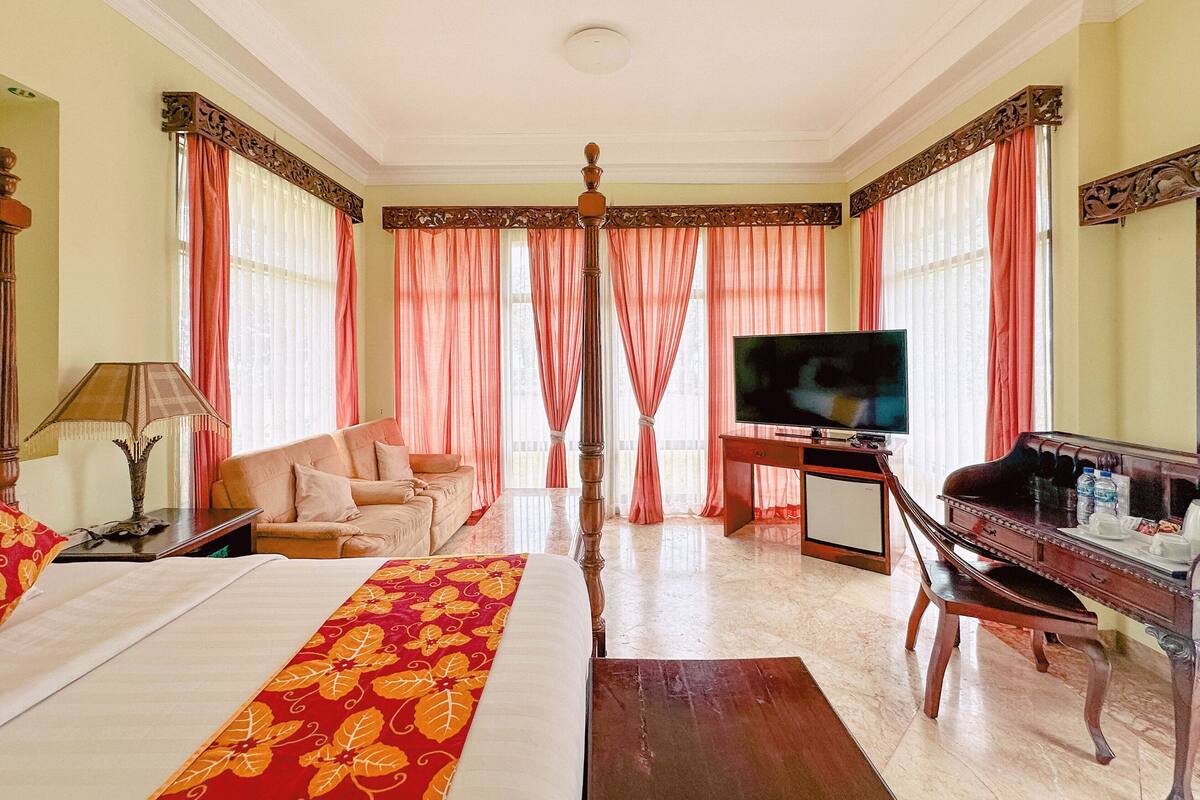 Una habitación de hotel con cama, escritorio, televisor y sofá.