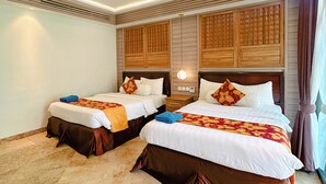 Habitación de hotel con dos camas, suelo de mármol, paneles de cabecera de madera y una mesita de noche con lámpara.
