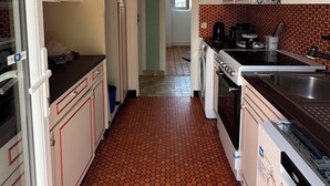 A kitchen with a tiled floor, a washing machine, a stove, and cabinets.