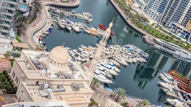A marina with numerous boats docked, a prominent dome structure, and modern buildings in the background. - Marina View, Fully Furnished, Close to Marina Walk (Dubai)