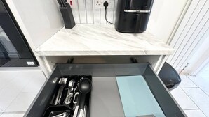 A kitchen with a marble countertop, a black coffee maker, and a drawer with utensils. - New and stylish home (Southsea)