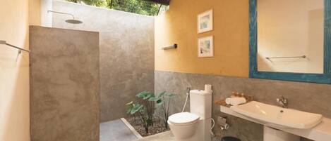 Een badkamer met een douche, toilet, wastafel en een spiegel.