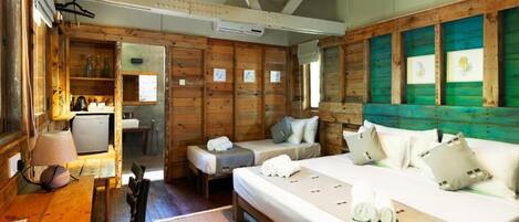 A wooden cabin with two beds, a small kitchenette, and a dining area.